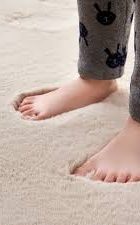 Barfüßige Füße stehen auf einem weichen, flauschigen Teppich mit Abdrücken.